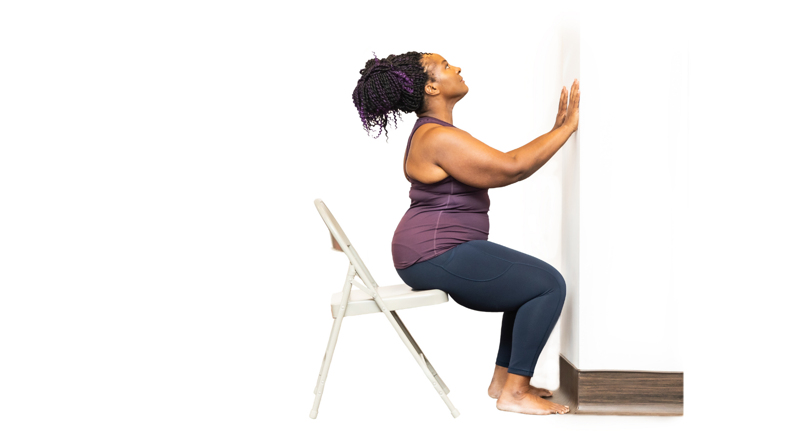 Yoga Student practicing Cobra Pose (Bhujangasana) with chair and at the wall to assist her