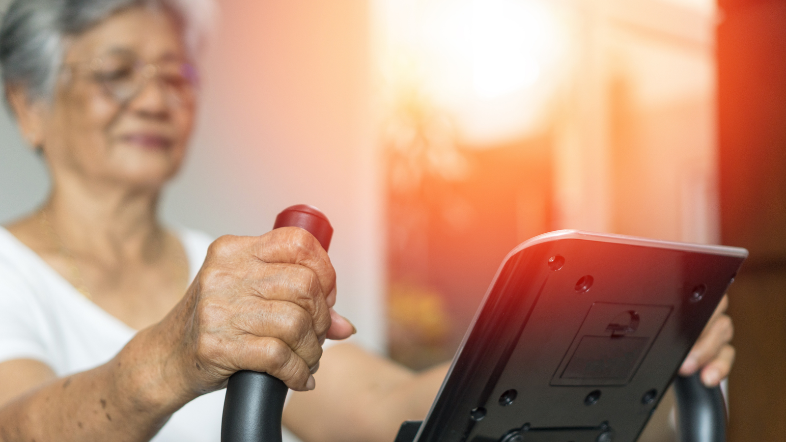 Active Asia senior woman doing training exercises on Stationary bike for greater health and wellbeing