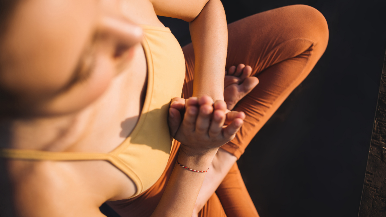 young woman in activewear sitting in lotus pose keeping hands in namaste for relaxing meditation