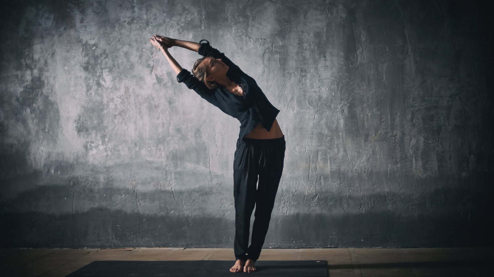 Beautiful woman practices yoga asana Talasana or Palm Tree Pose variation