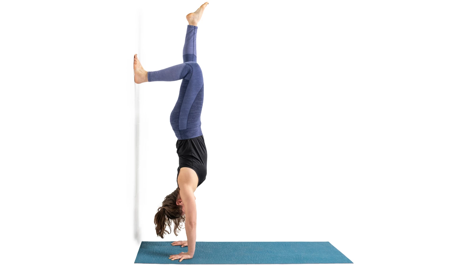 Beginner yoga student enjoying the benefits of a variation of Handstand Pose at a wall (Sanskrit name: Adho Mukha Vrksasana)