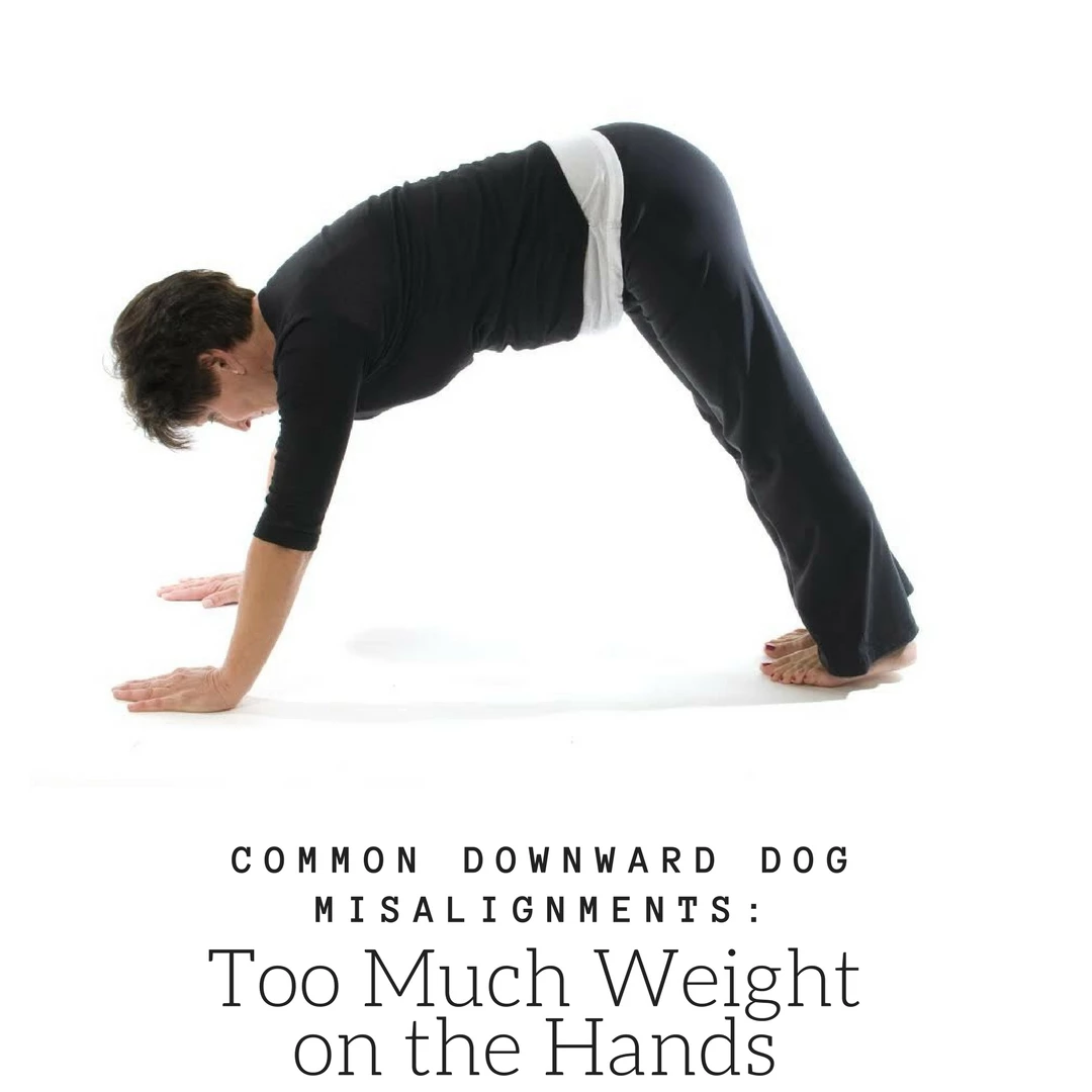 A woman in downward facing dog, (Adho Mukha Svanasana) in a common misalignment: too much weight on the hands