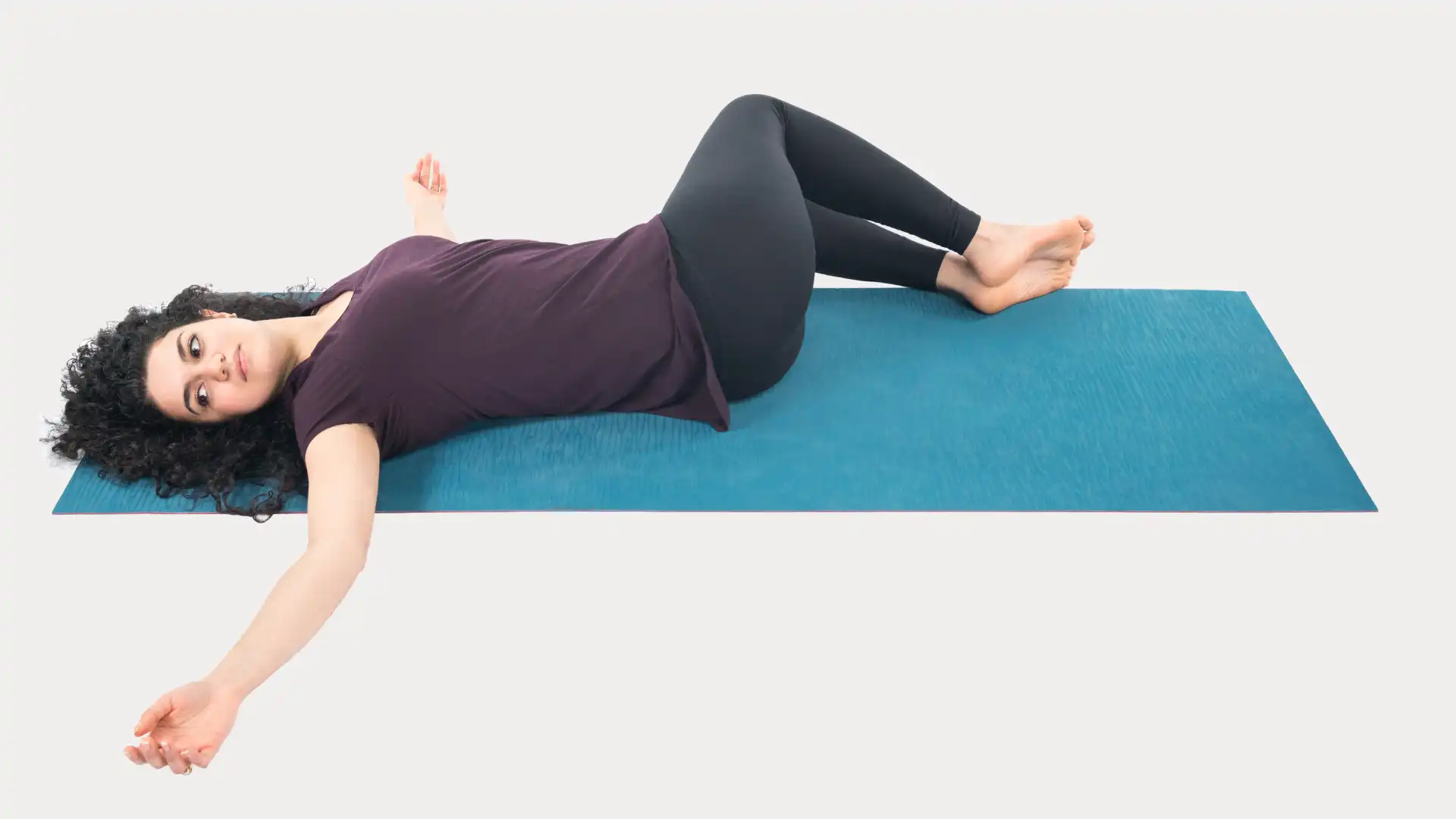 Woman practicing yoga supine twist.