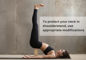 A woman in Shoulderstand (Salamba Sarvangasana) using a block under her lower back to help protect the neck from pain or injury.