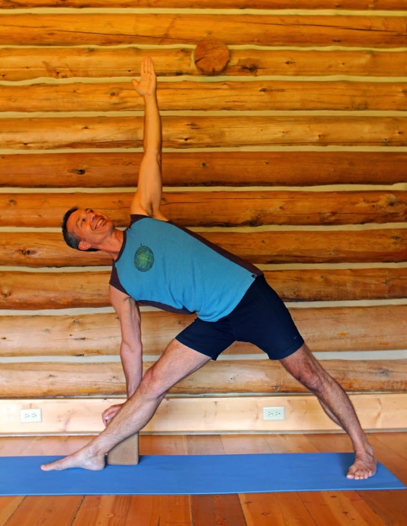 Dr. Baxter Bell practicing triangle pose (Trikonasana) with block a standing yoga pose for healthy feet.