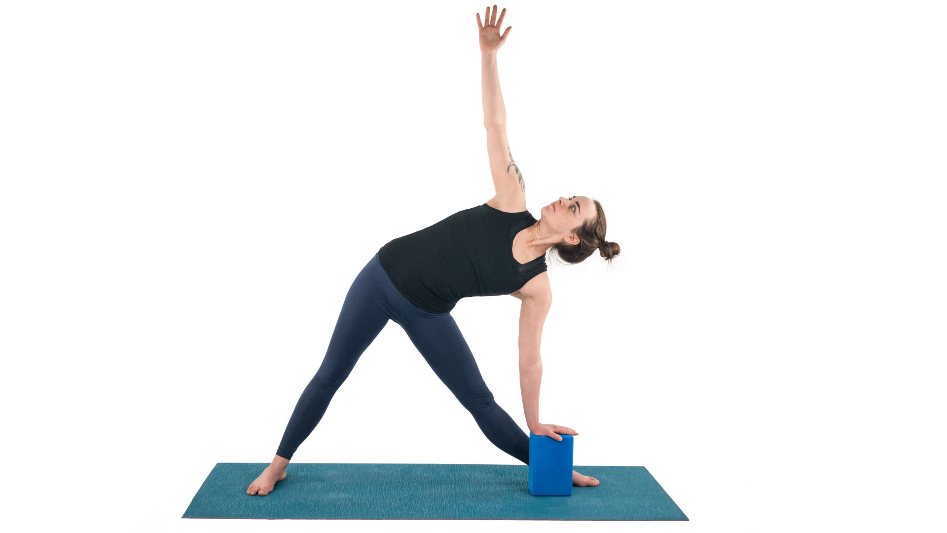 Woman practicing triangle pose with a block.