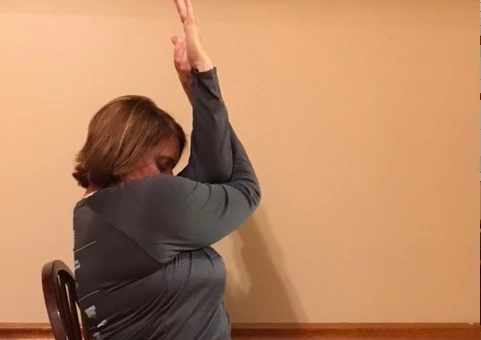 Woman practicing yoga for neck and shoulder pain, in Eagle Arms pose (Garudasana) with Chin Tilt