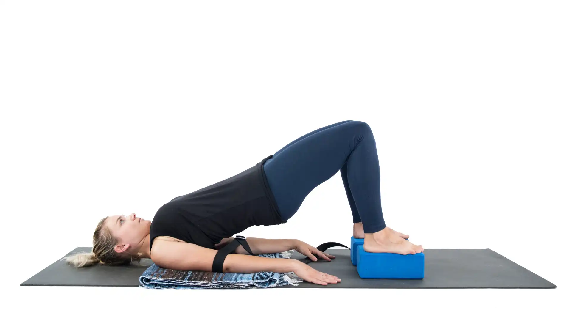 Woman practicing bridge pose variation using props.