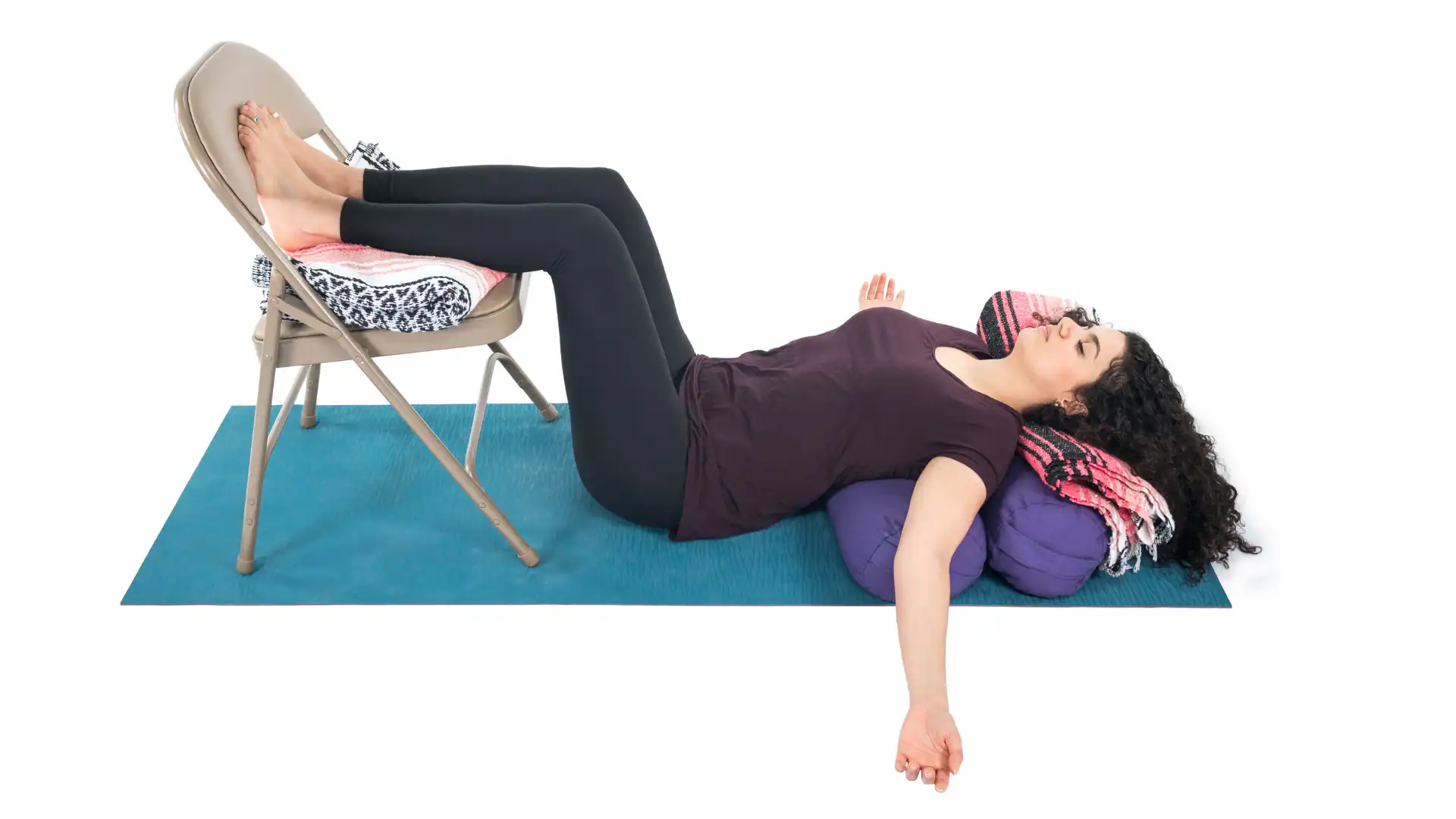 Woman practicing restorative bridge pose with props.