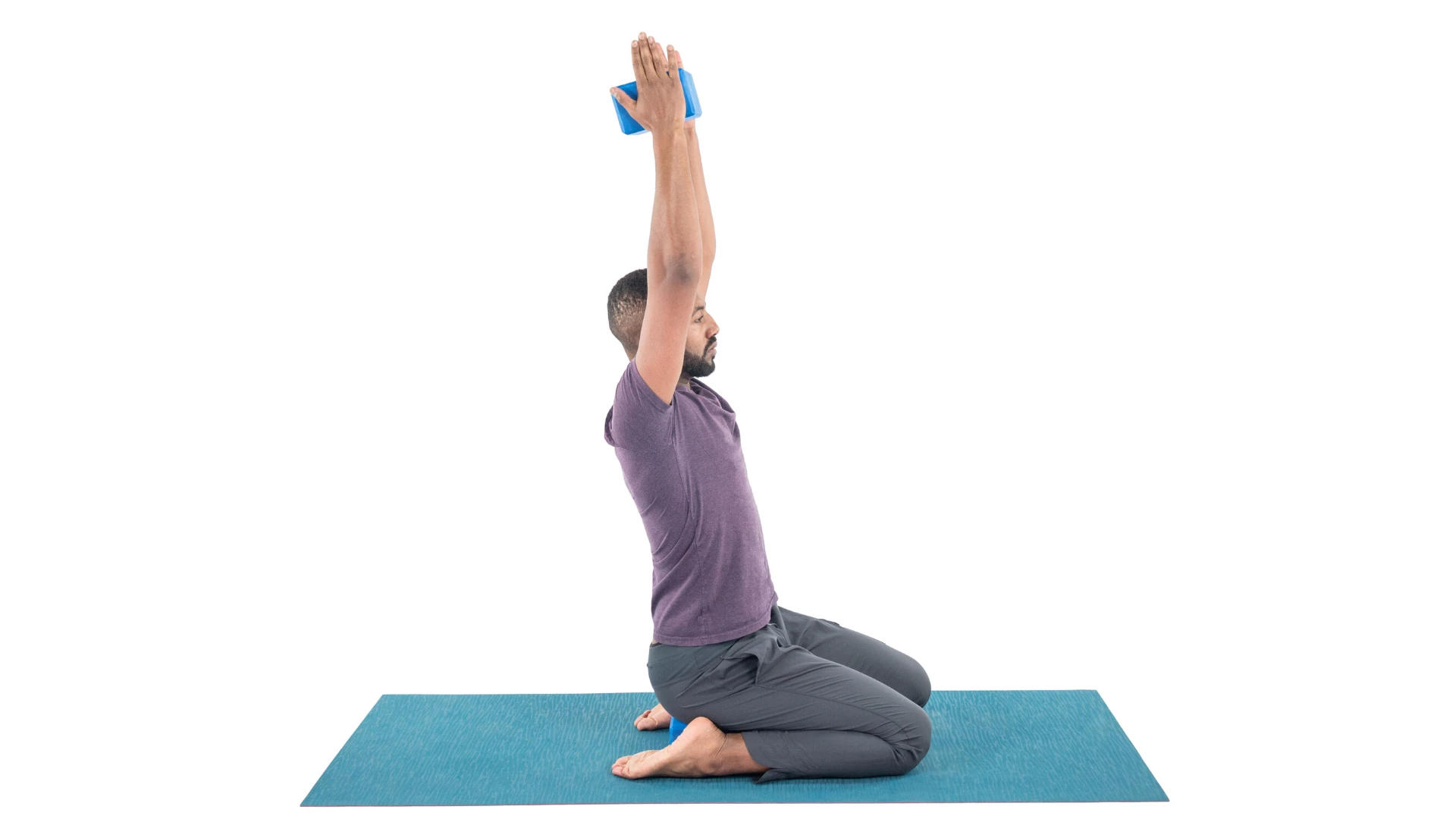 Man practicing hero pose variation with block between hands overhead.