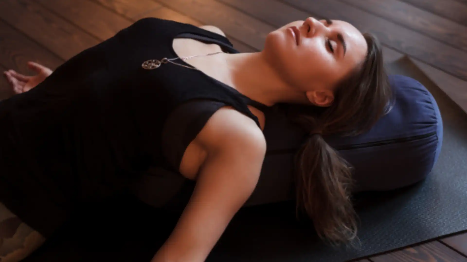 Woman resting with her back supported by a yoga bolster