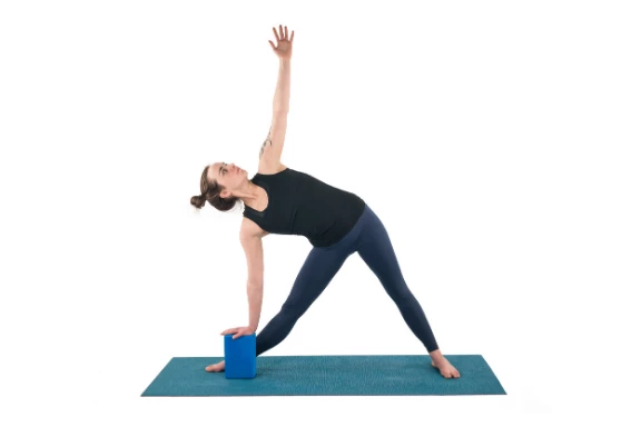 Woman practicing yoga triangle pose with a block