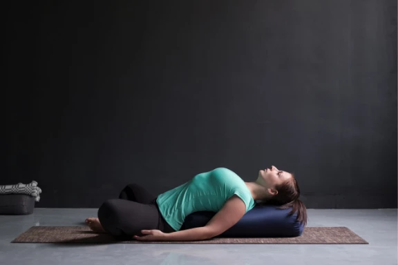 Woman practicing supported backbend with yoga bolster