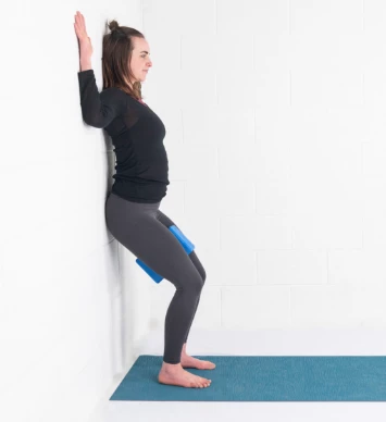 Utkatasana, fierce pose, chair pose, pose to strengthen legs and the core, pose at the wall with blocks for strengthening