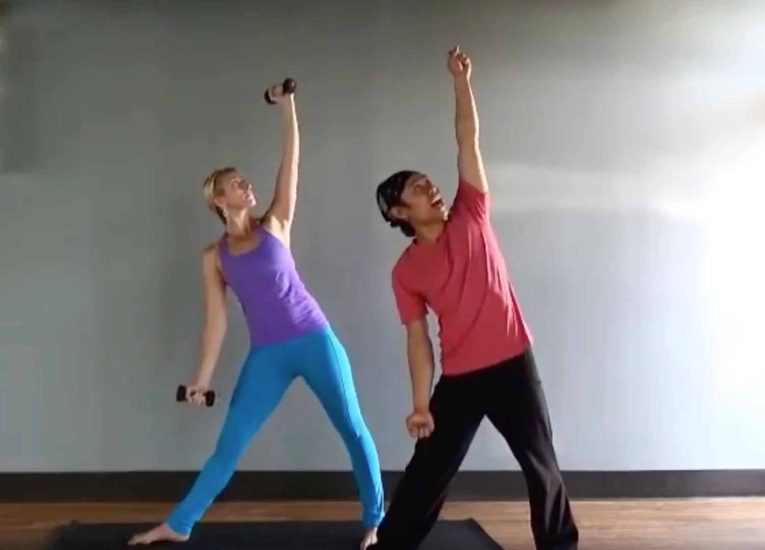 nolan lee teaching woman practicing yoga triangle pose with weights