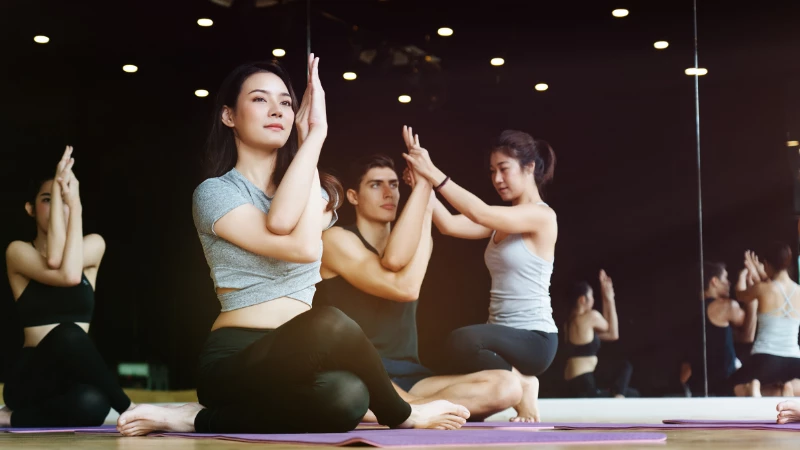 Yoga teacher using empowering language to help students with Eagle Pose arms