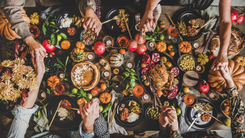 thanksgiving feast holding hands at the table - a yoga holiday practice