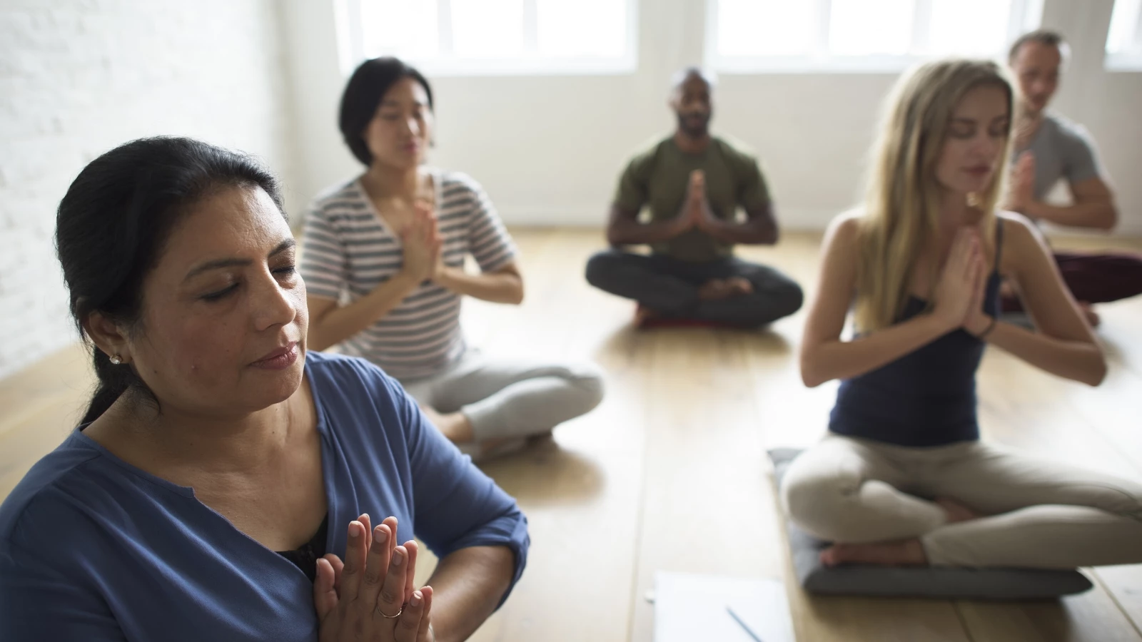 Group of diverse yoga students practicing meditation.