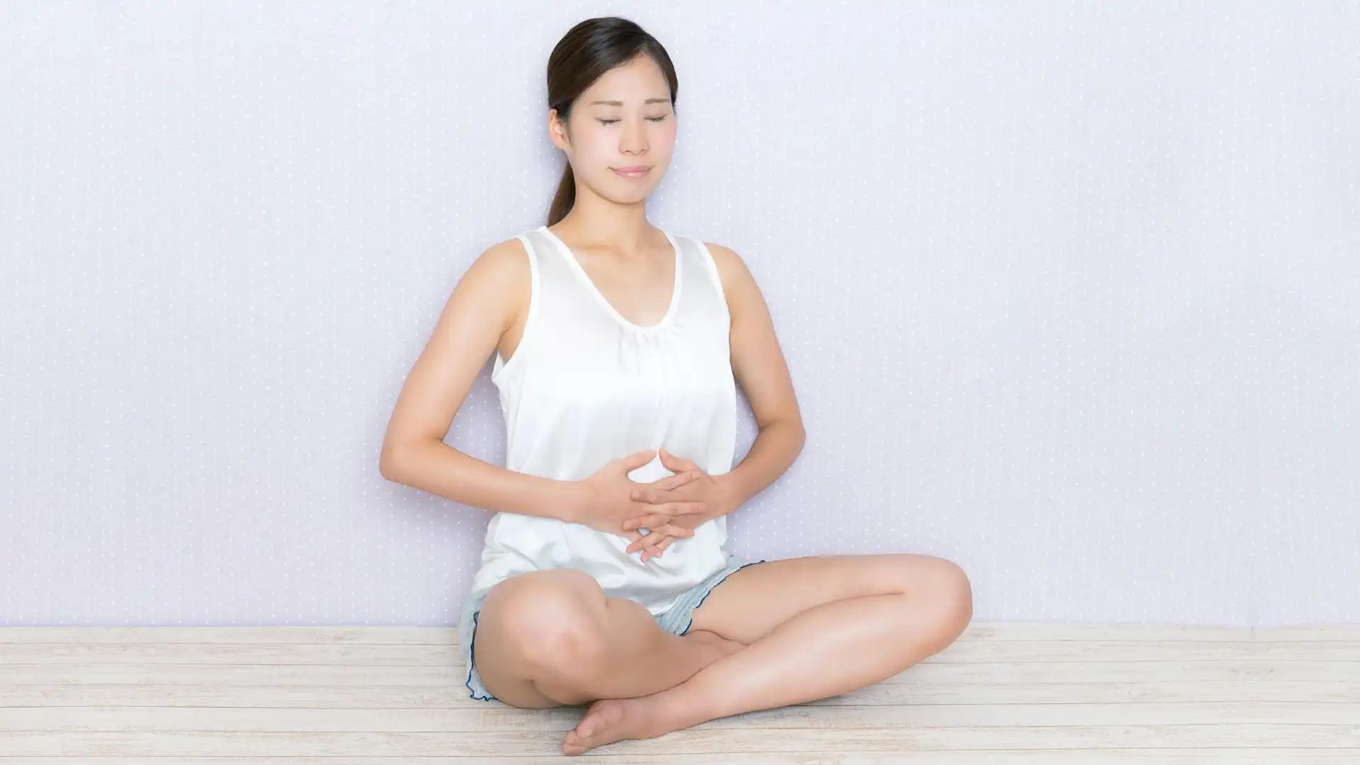 Woman holding belly while meditating.