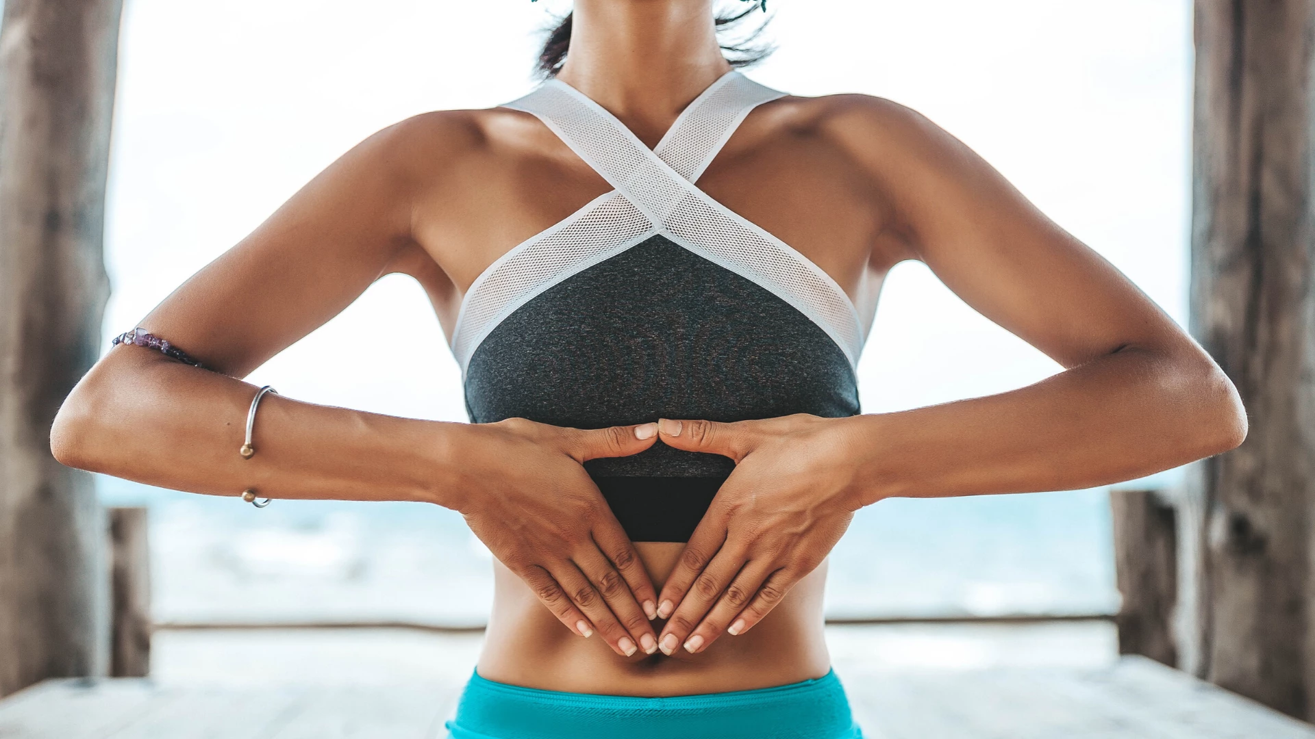 Woman practicing yoga meditation with hands on solar plexus.