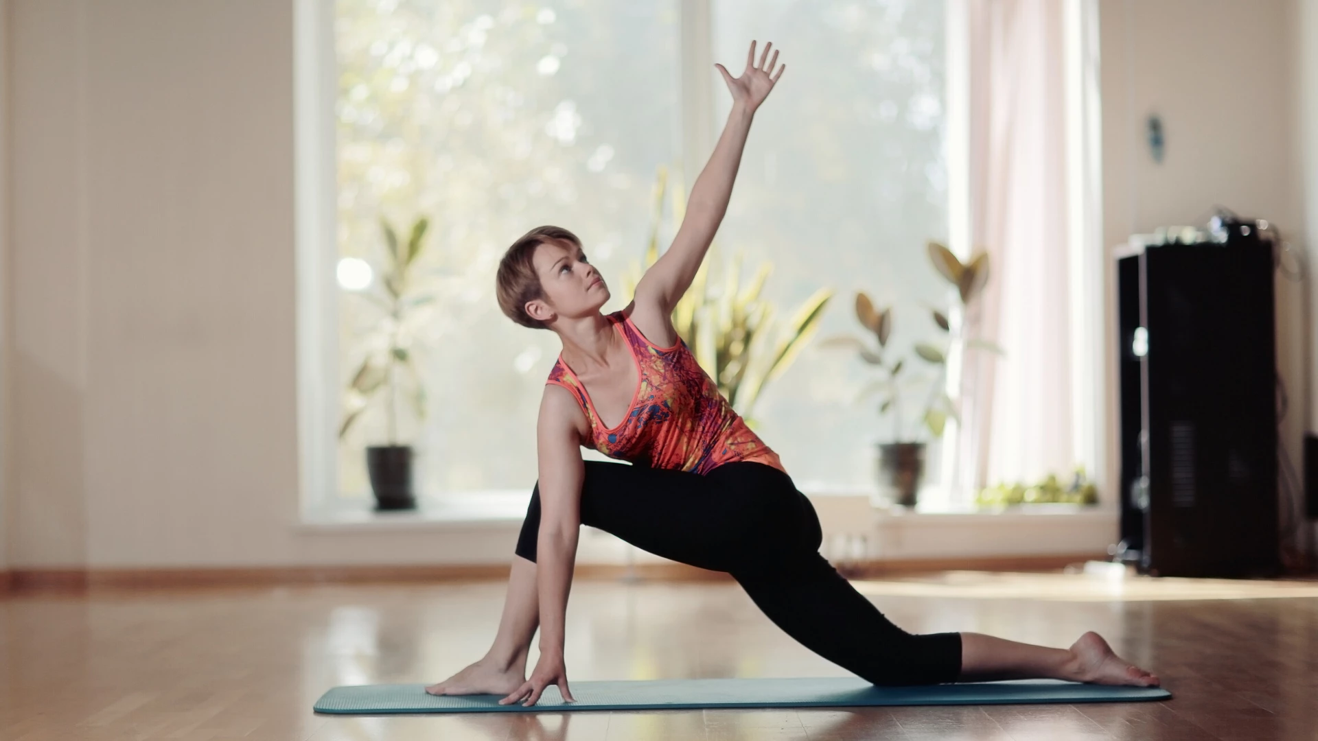 Woman practicing revolved low lunge pose in yoga studio.