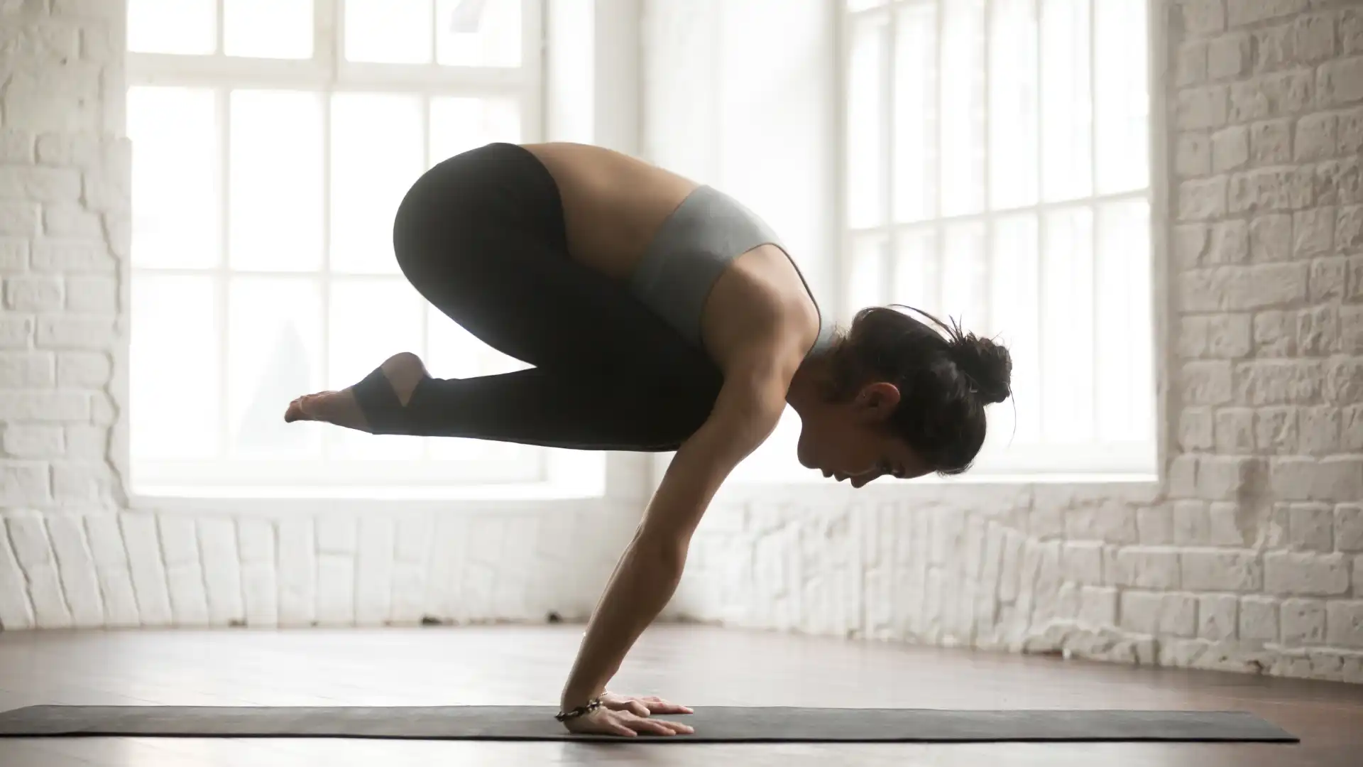 Woman practicing Yoga bakasana crow pose.