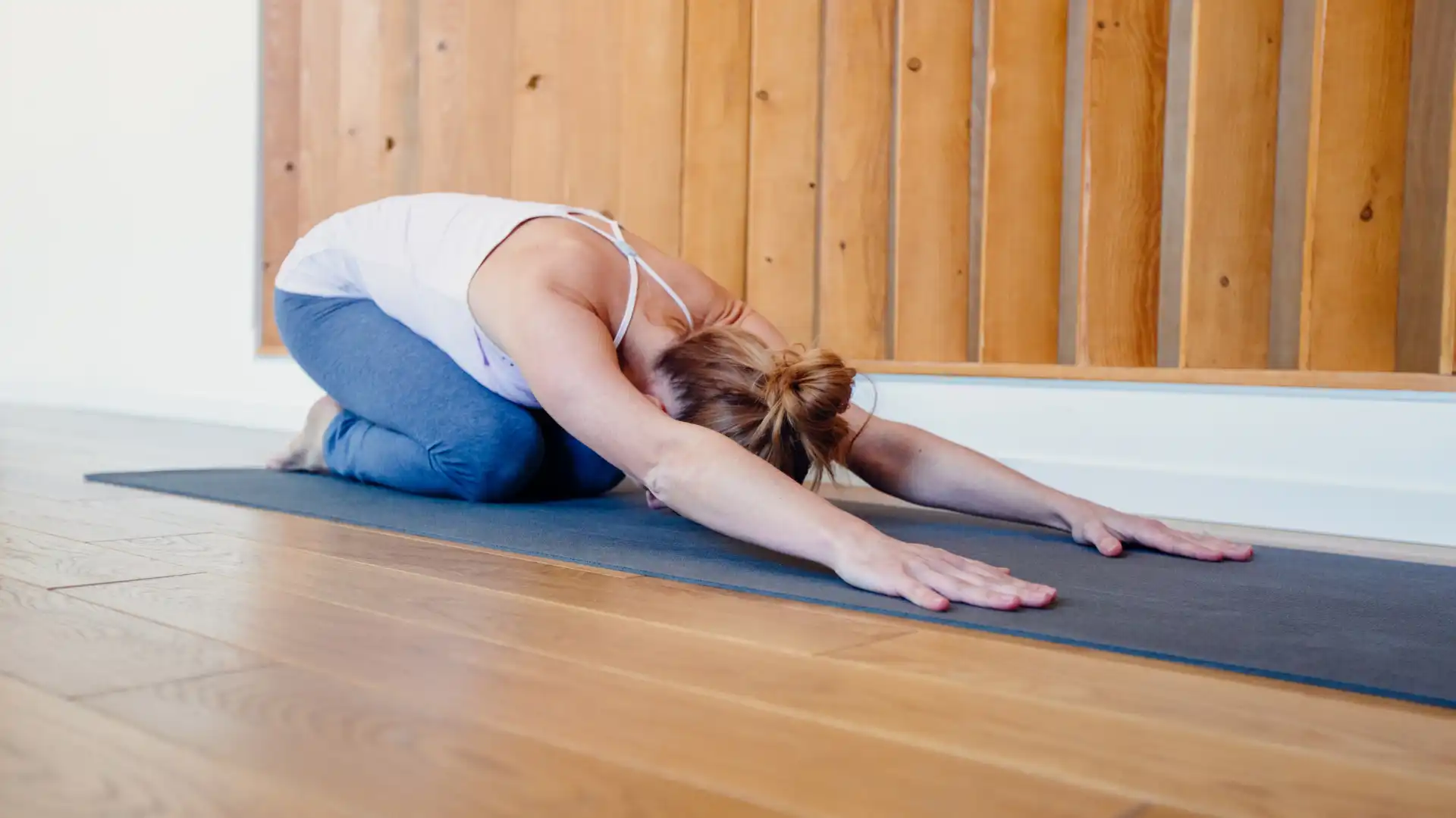 Woman practicing yoga child's pose.