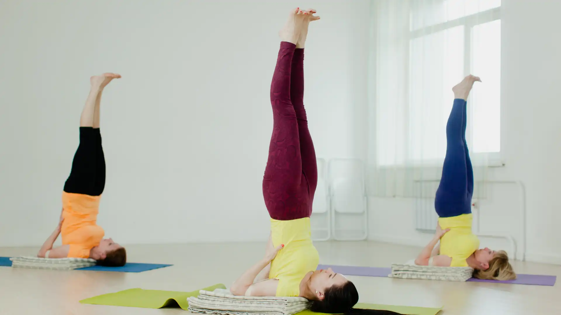 Group of yoga students practicing shoulder stand pose.