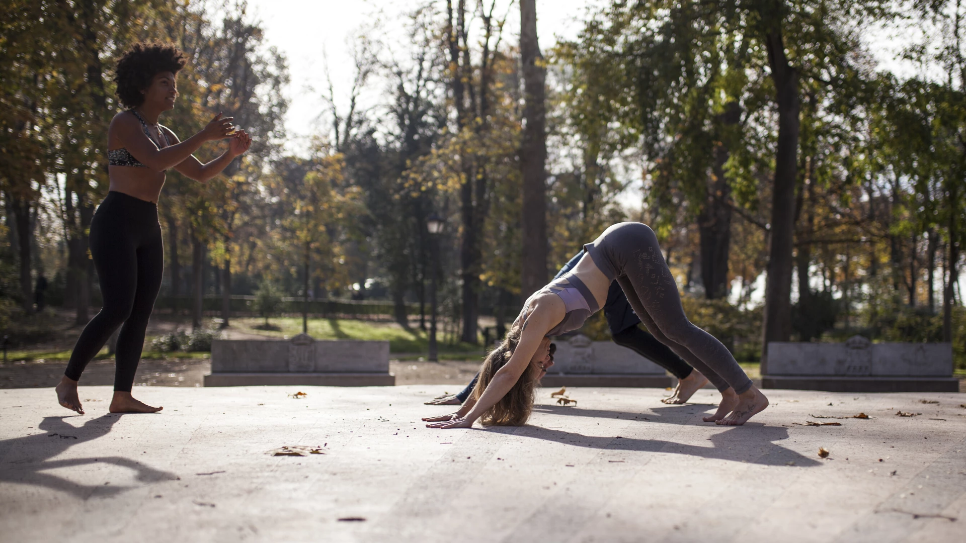 Yoga teacher instructing her students outside in downward facing dog.