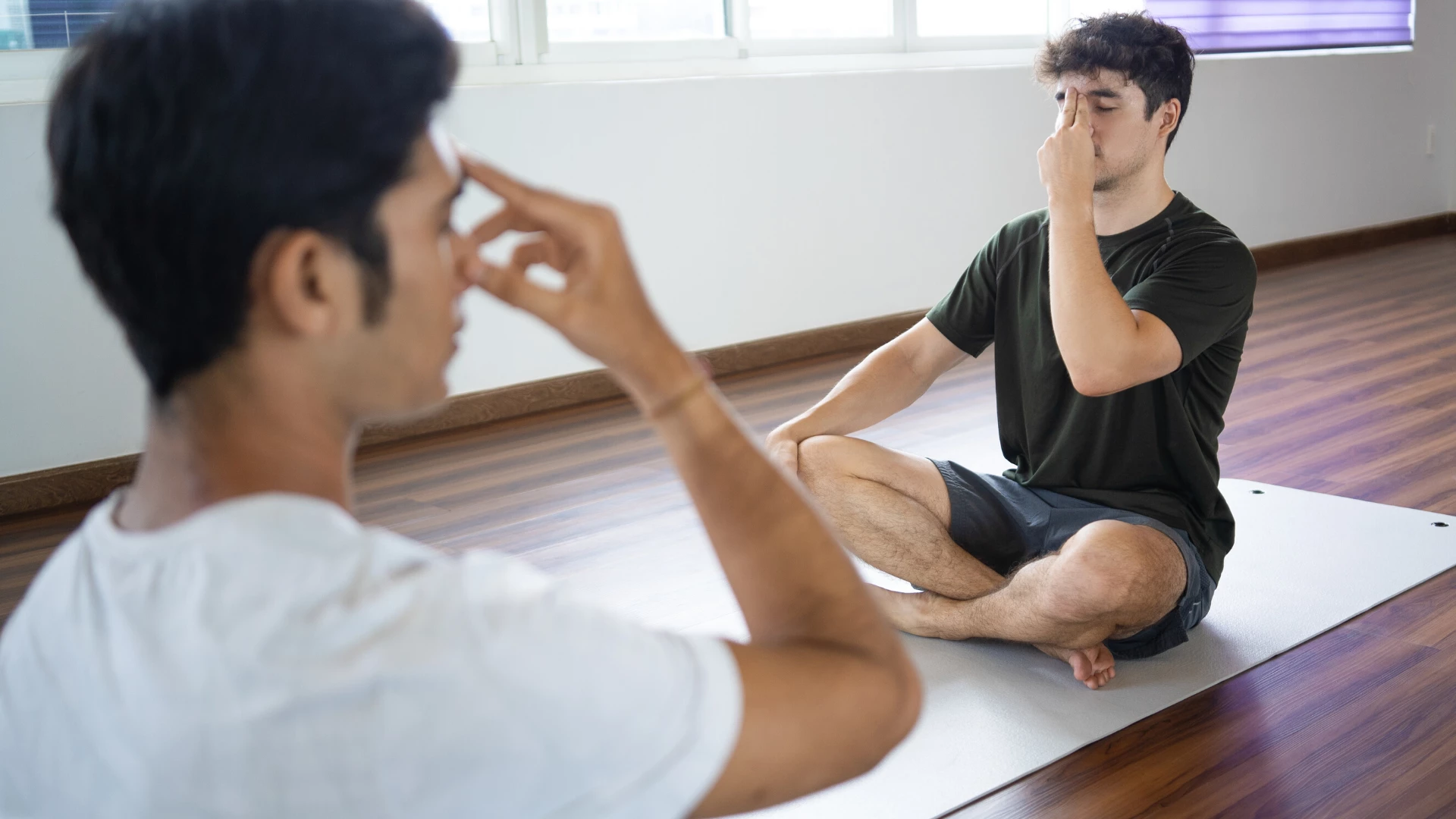 Two male yoga students practicing yoga breathing pranayama. 