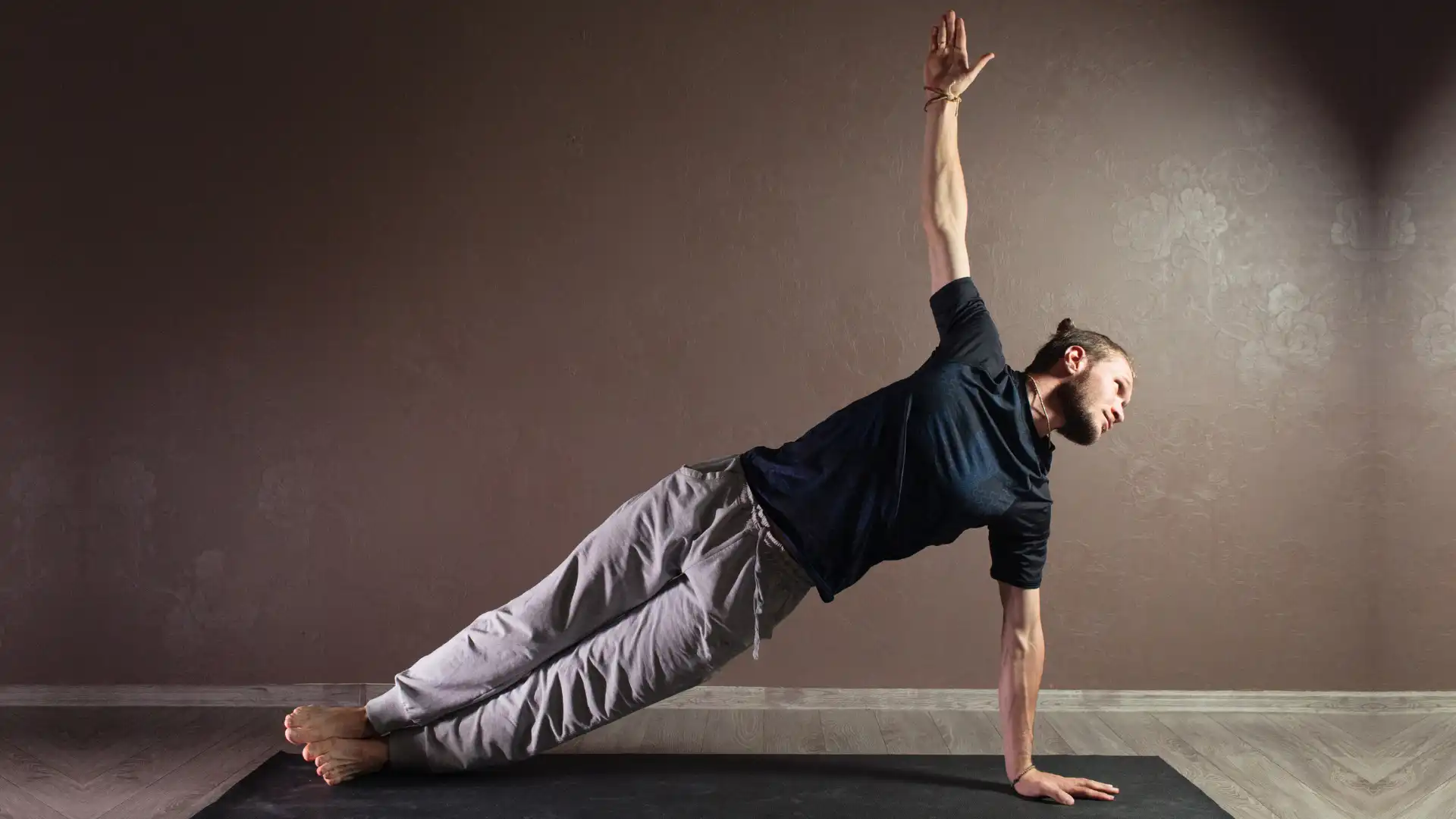 Male yoga student practicing vasisthasana side plank.