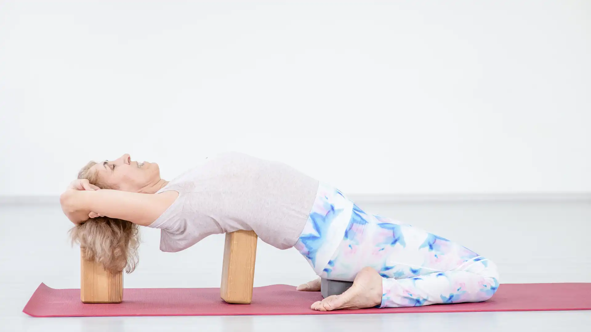 Woman practicing yoga supported hero pose supta virasana.