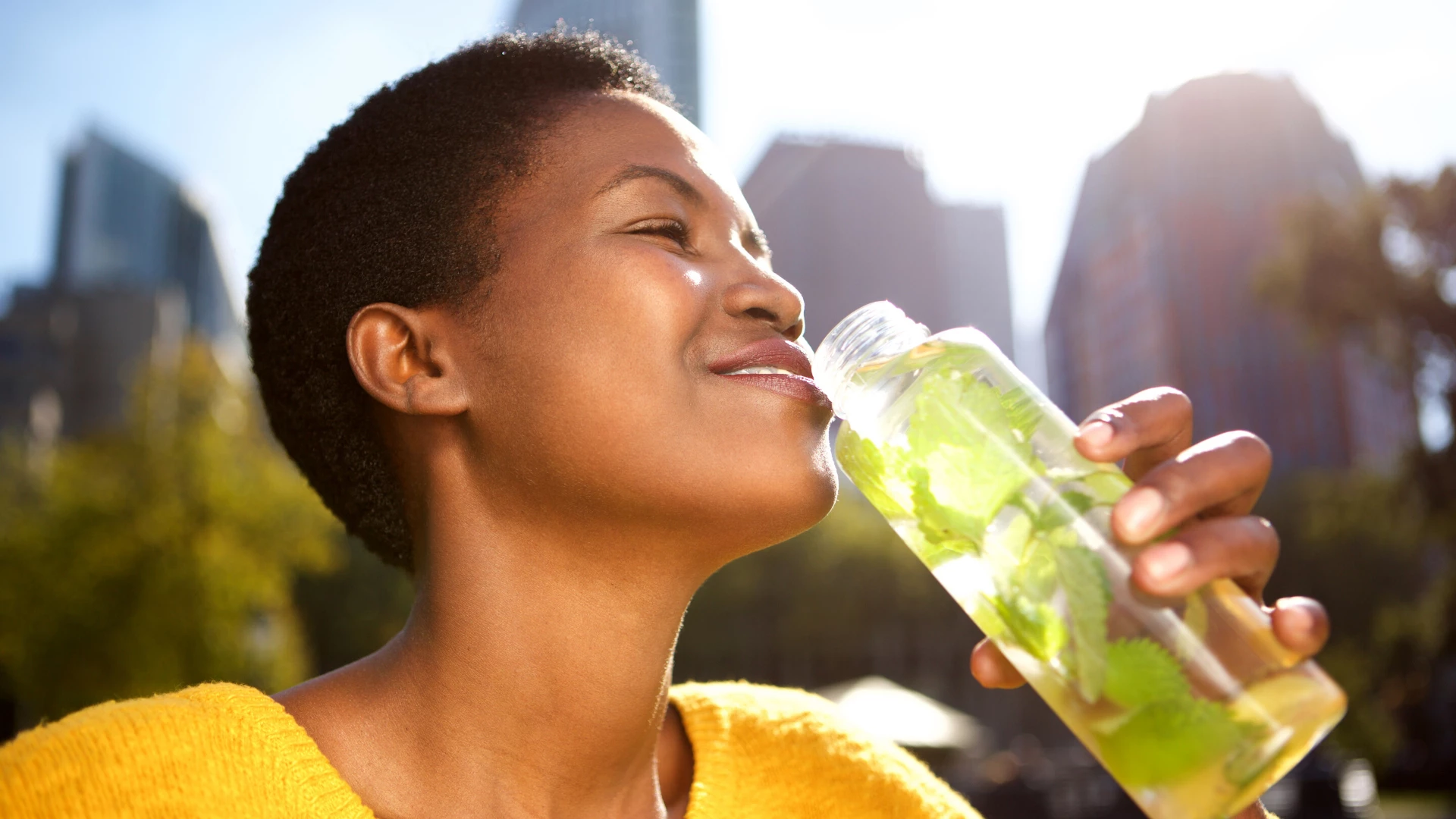 Yoga student drinking water outside.