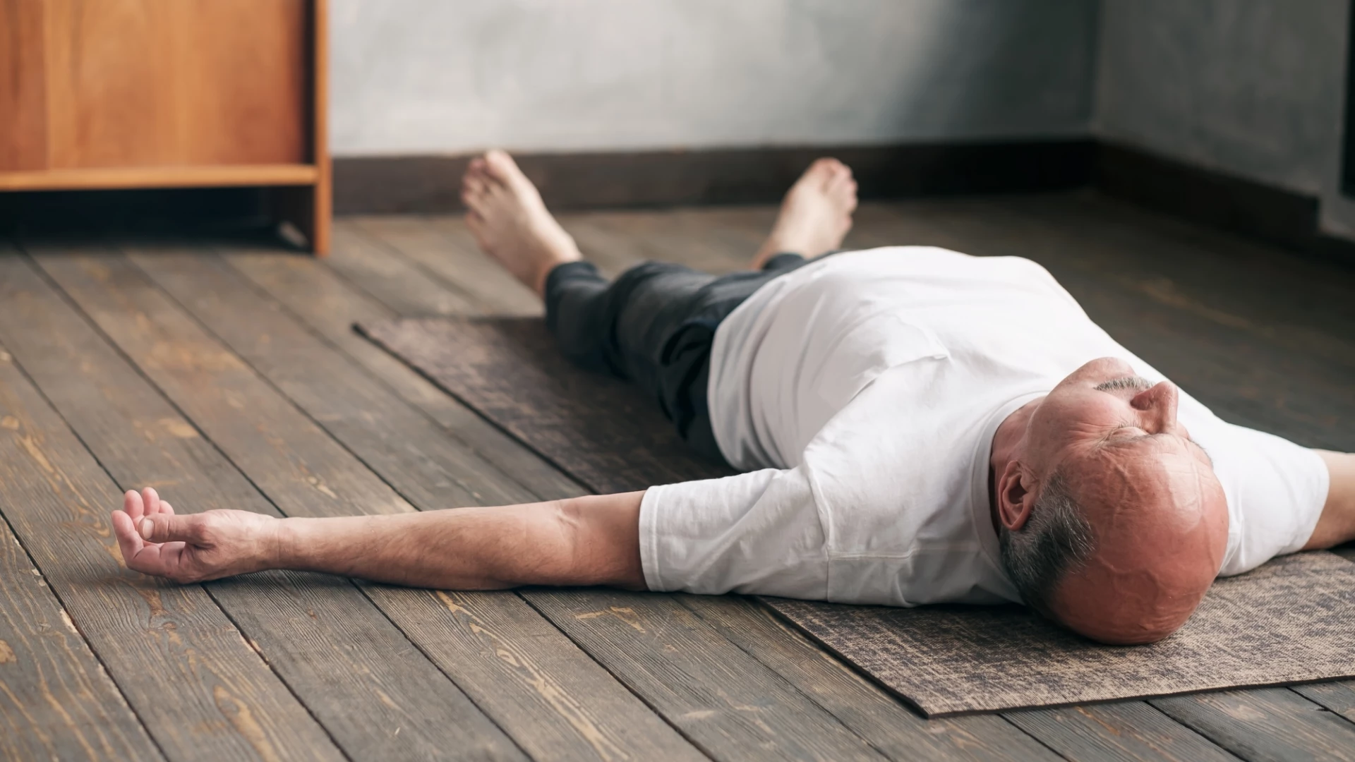 Older male yoga student practicing savasana.