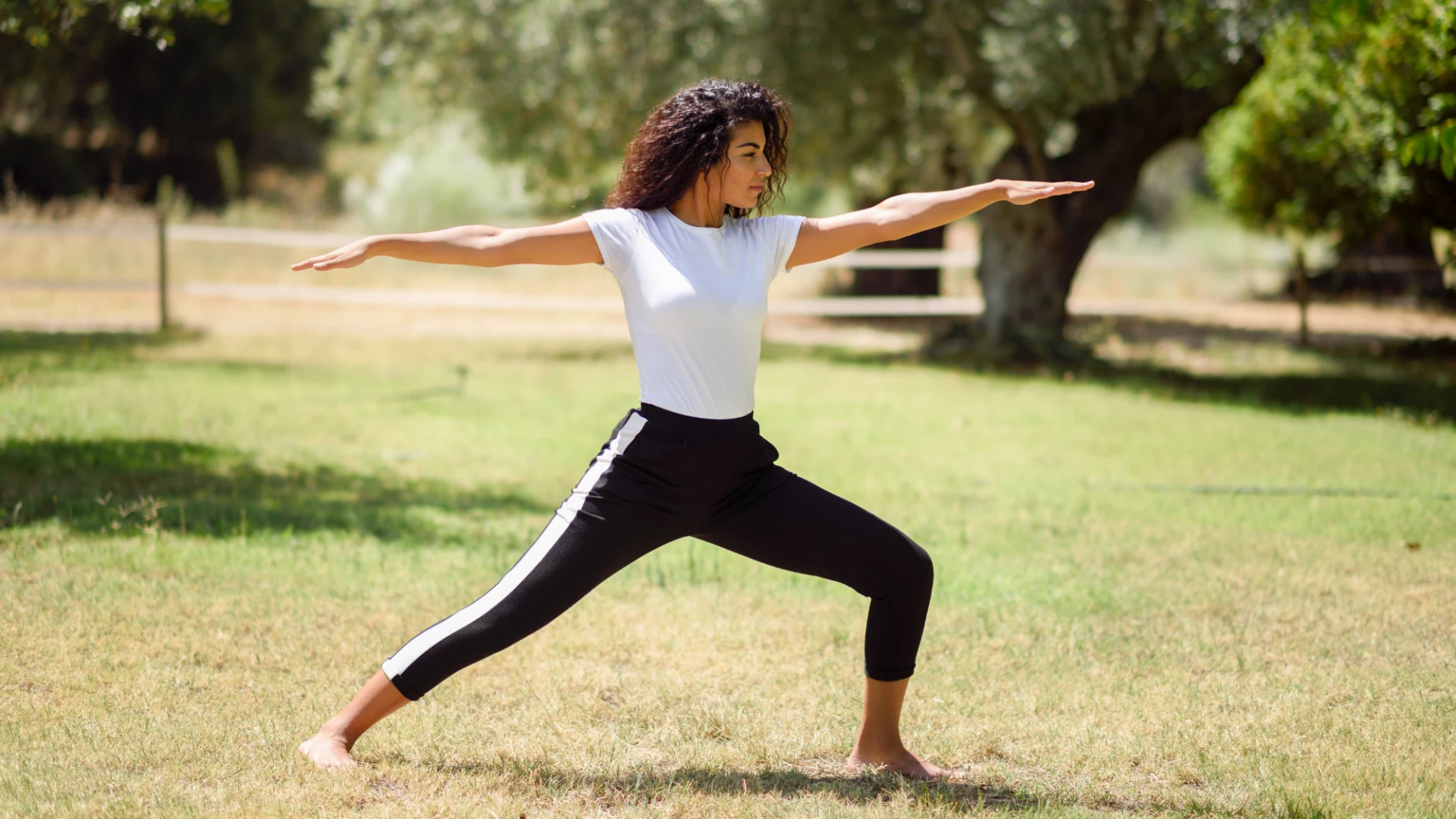 Yoga student practicing warrior II outside.