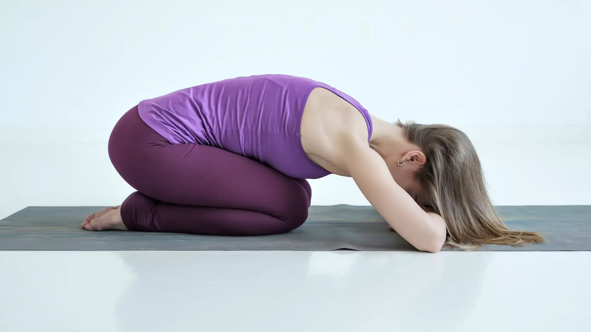 Woman practicing yoga child's pose.