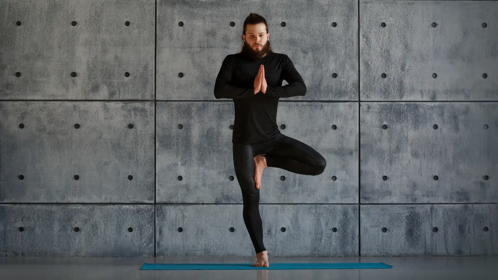 Male yoga student practicing vrksasana tree pose.