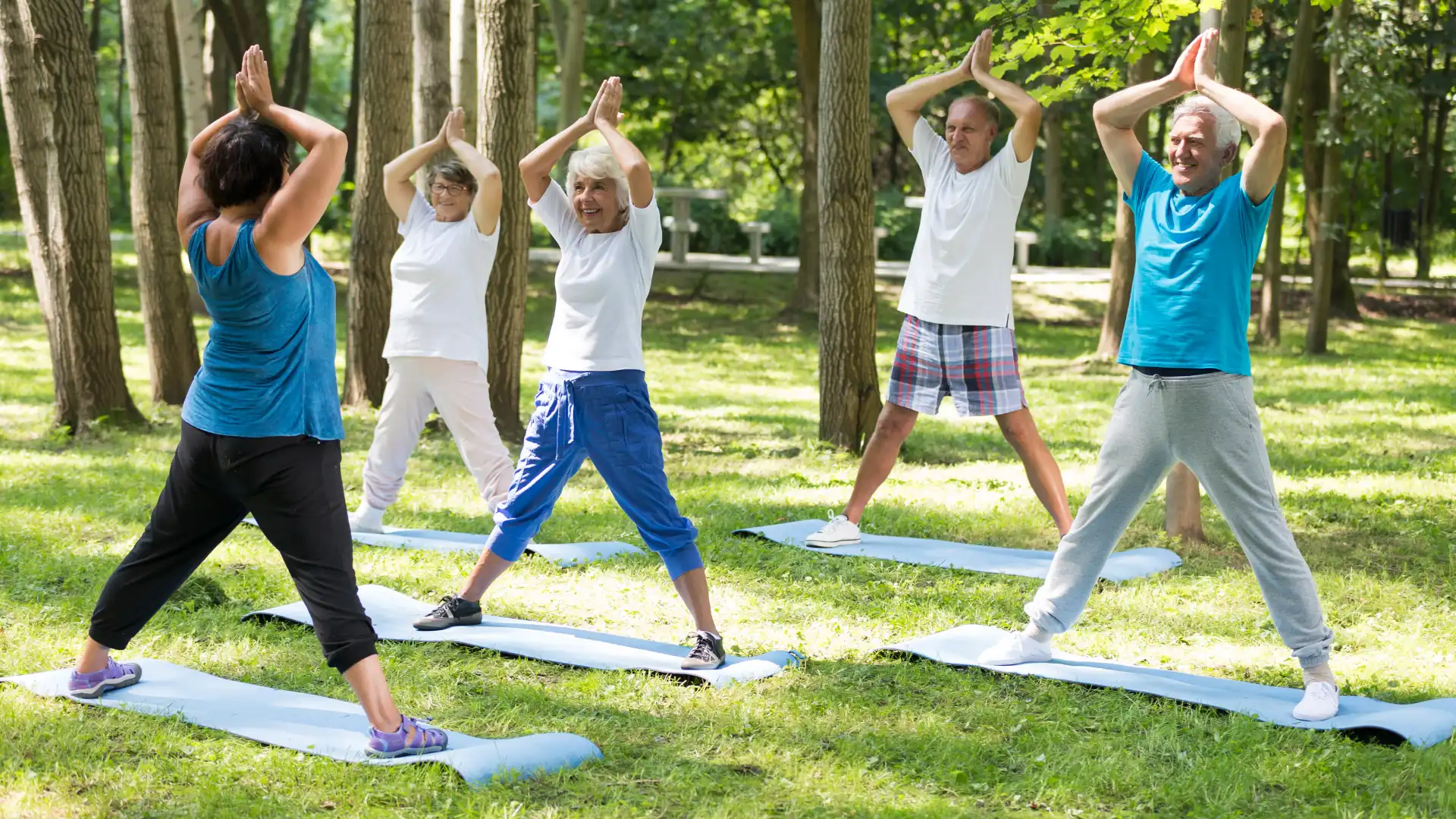 Group of older yoga students practicing yoga outdoors.