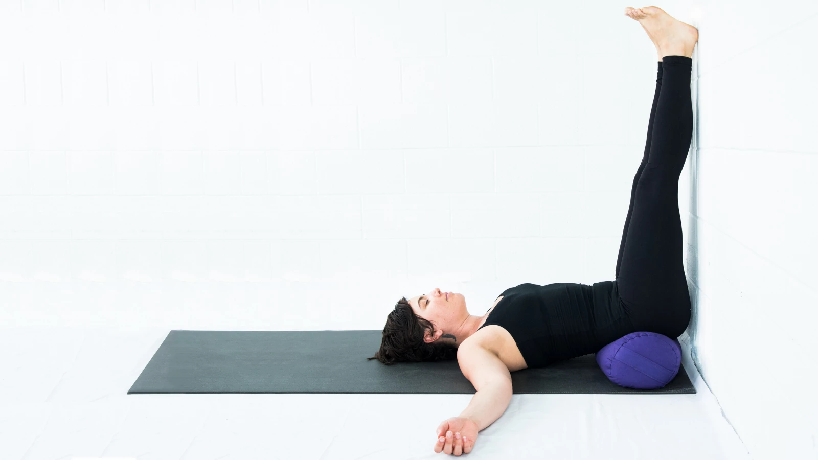 Female yoga student practicing viparita karani legs up the wall pose