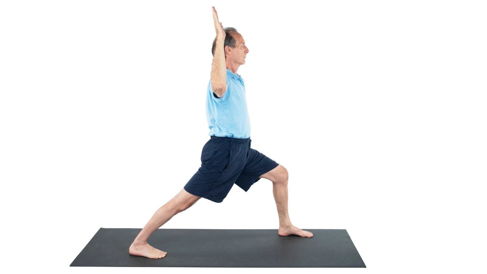 Older male yoga student practicing virabhadrasana I, warrior I pose