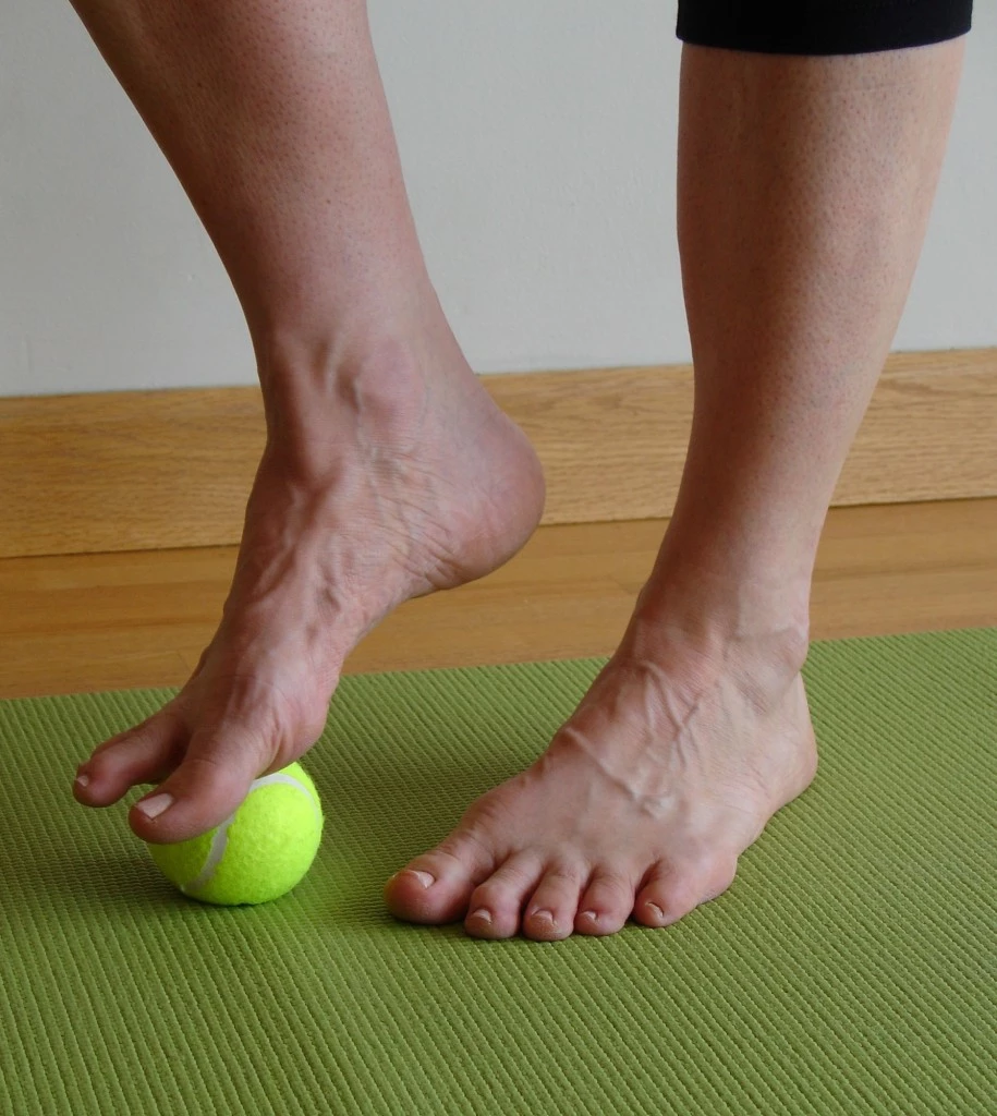 rolling your feet with a tennis ball to loosen tight hamstrings