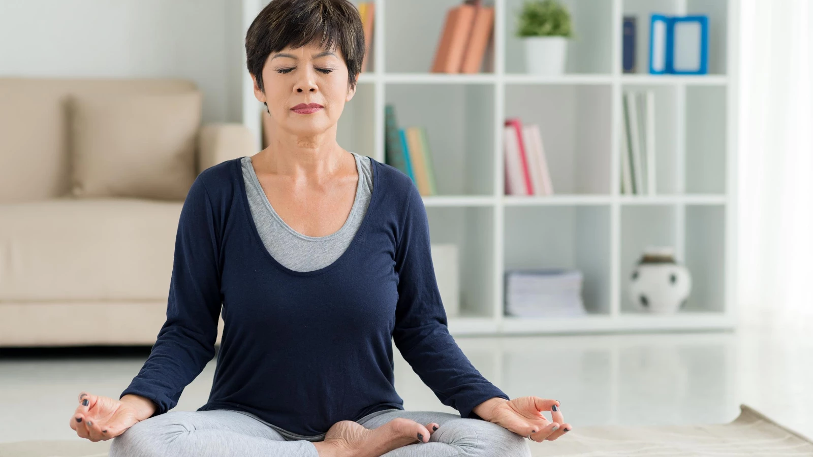 Older beginner practicing yoga for stress and brain health in Lotus Position on floor