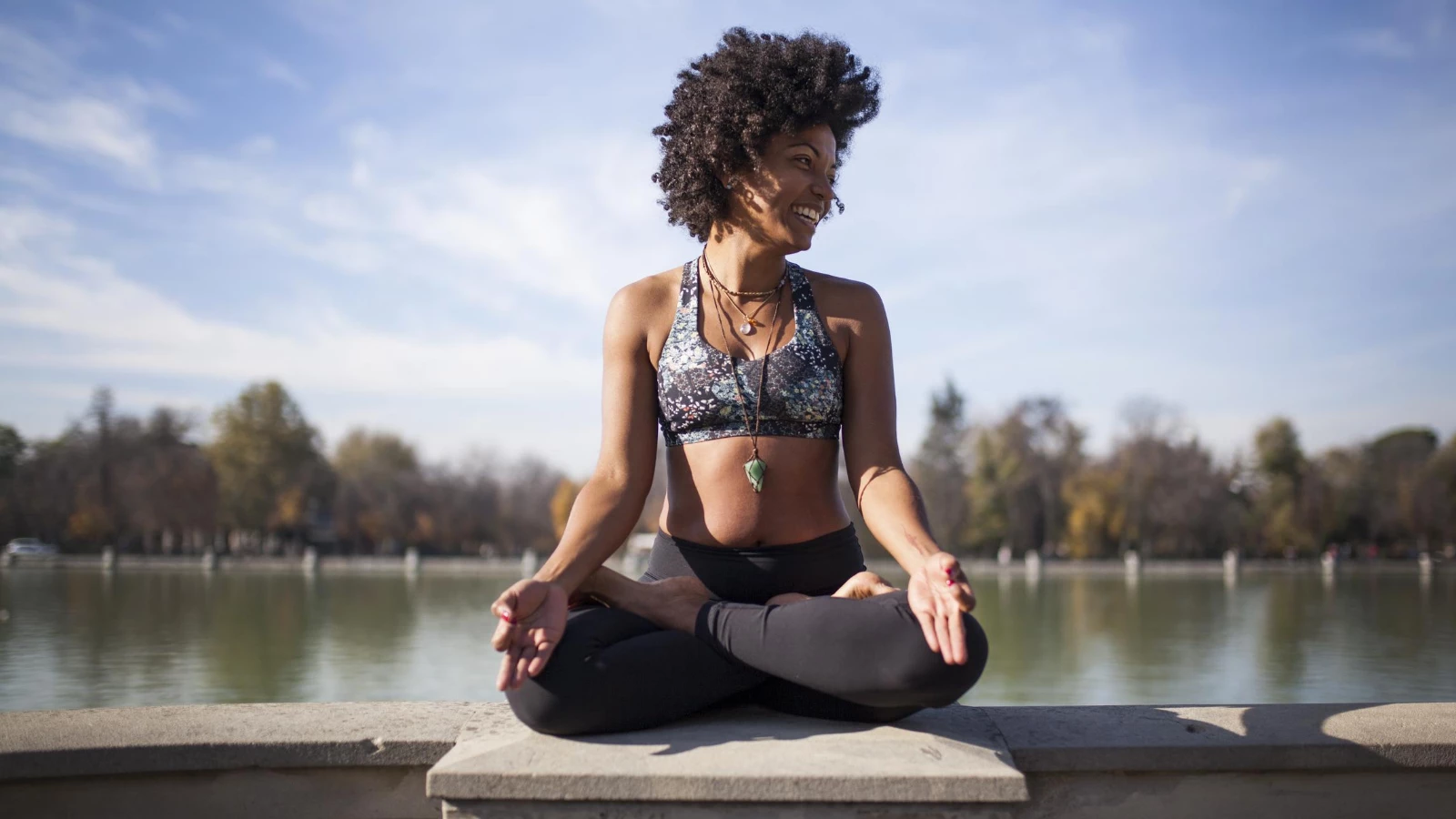 A yoga student practicing outside in Lotus Pose (Sanskrit name: Padmanasana) to reduce stress and maintain equanimity and stability