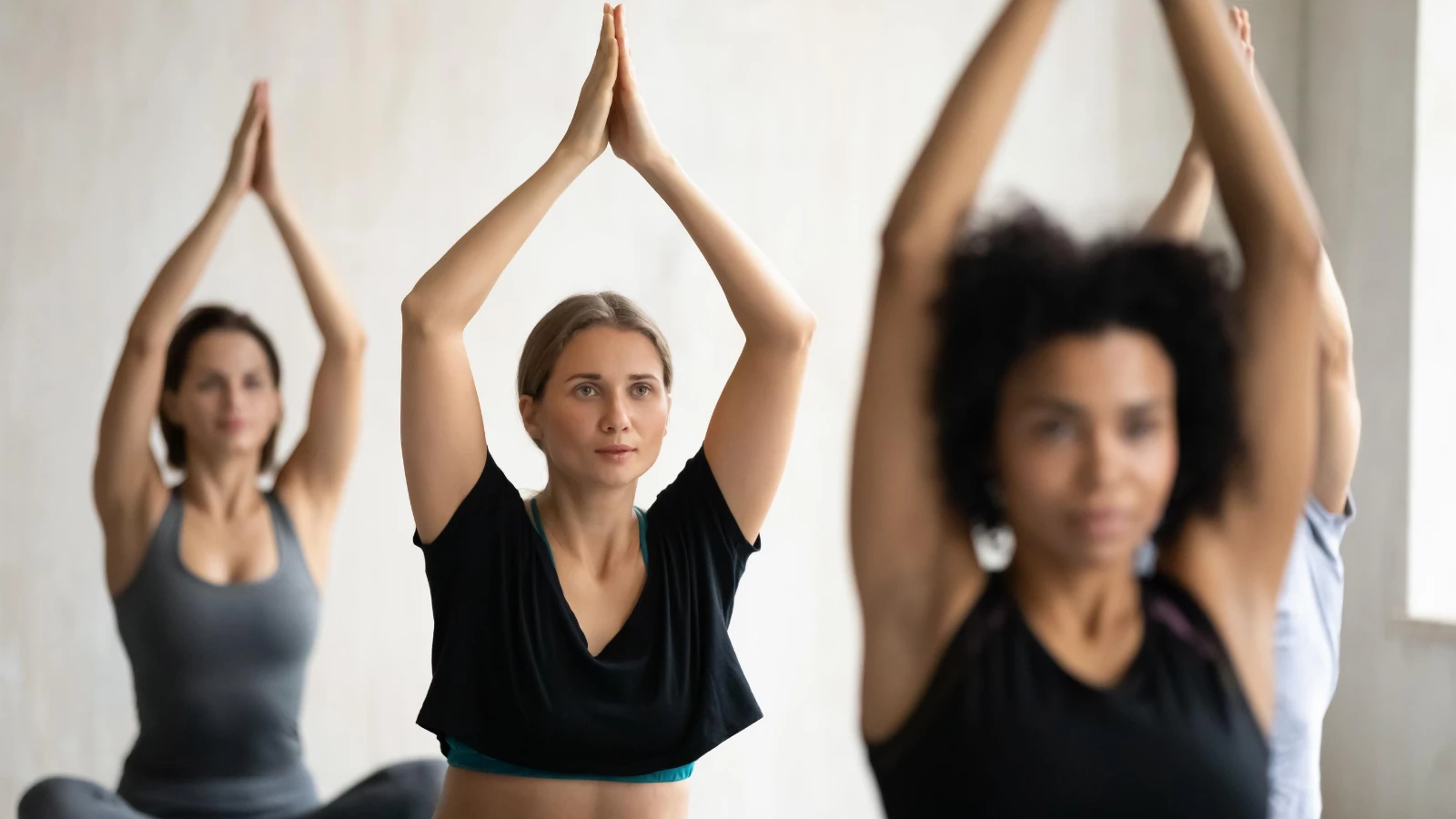 Yoga students in class in Lotus Pose (Sanskrit name: Padmasana) enjoying the benefits of reduced anxiety and stress from yoga