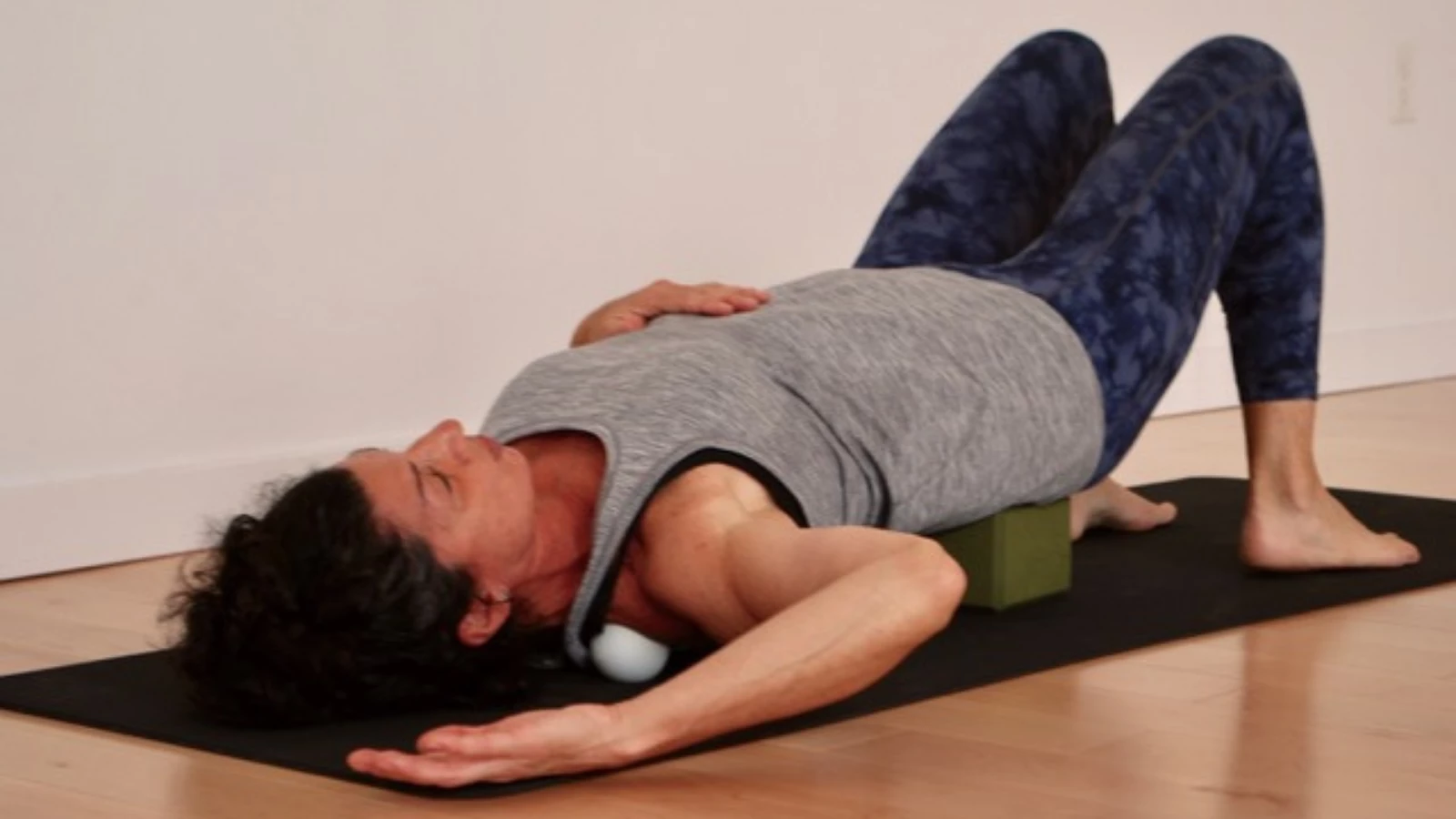 A yoga student in class practicing myofascial release with the use of a yoga block and props