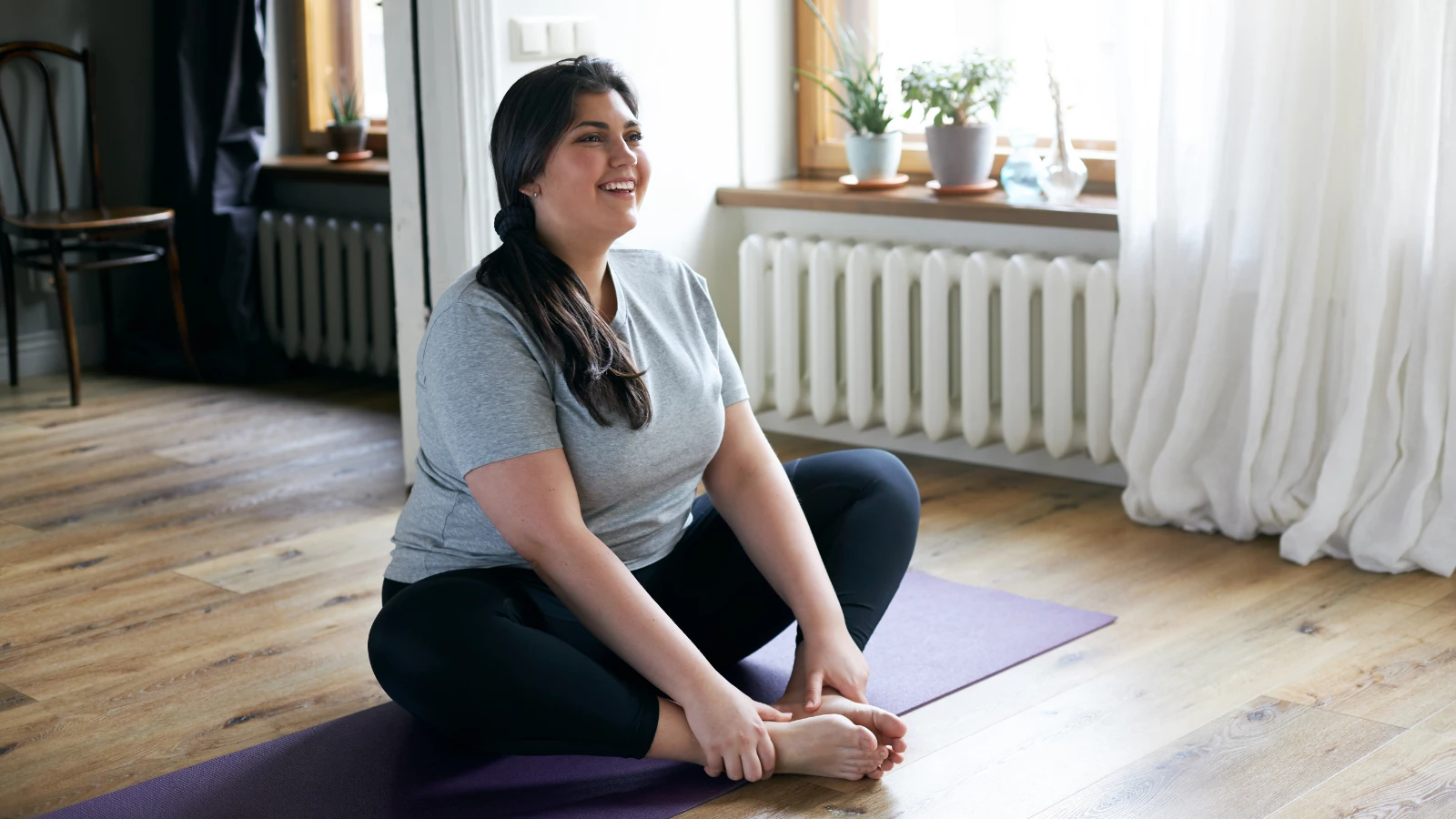 Yoga student experiencing the benefits of yoga to practice mind-body connection and intuitive eating in Bound Angle Pose (Sanskrit name: Baddha Konasana)