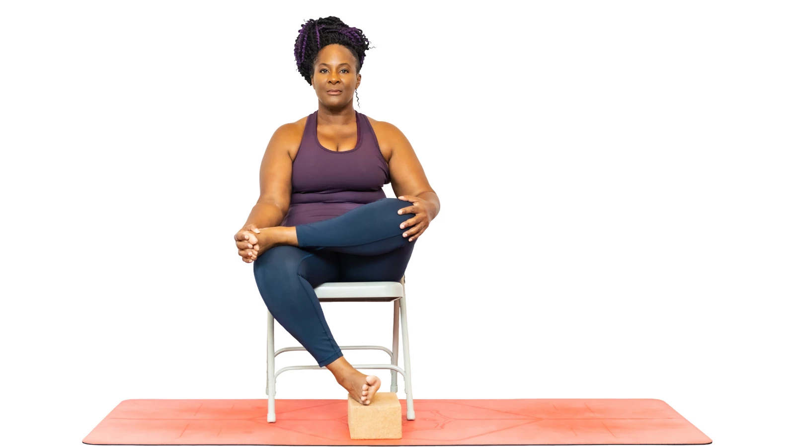 Yoga teacher practicing a modified version of Fire Log Pose (Agnistambhasana) seated in a chair