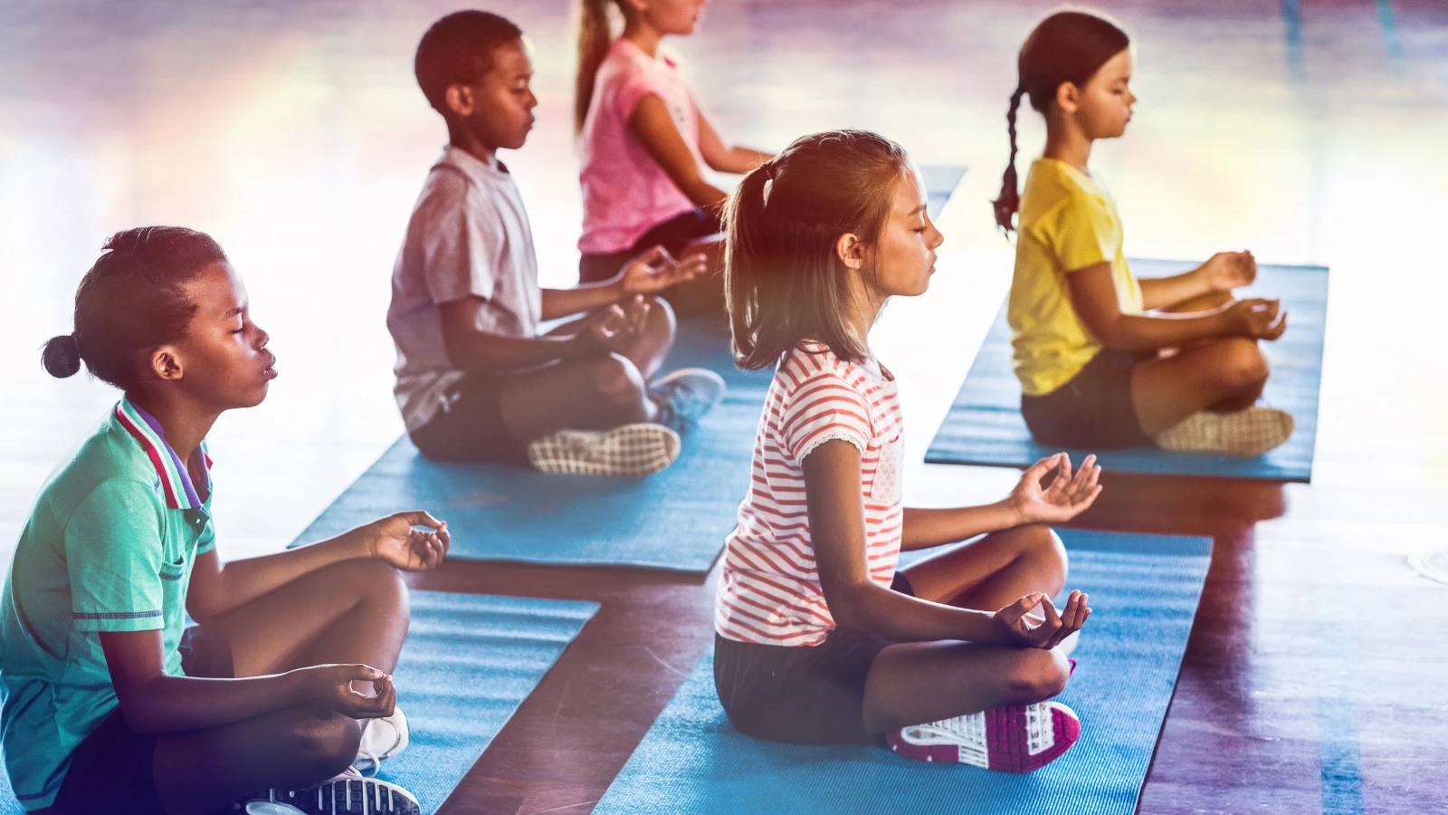 Kids in yoga class experiencing the benefits of yoga on their general ease and calm