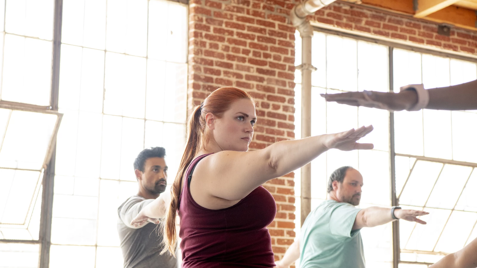 Yoga students practicing Warrior II Pose in class to help reduce stress and engage the autonomic nervous system response