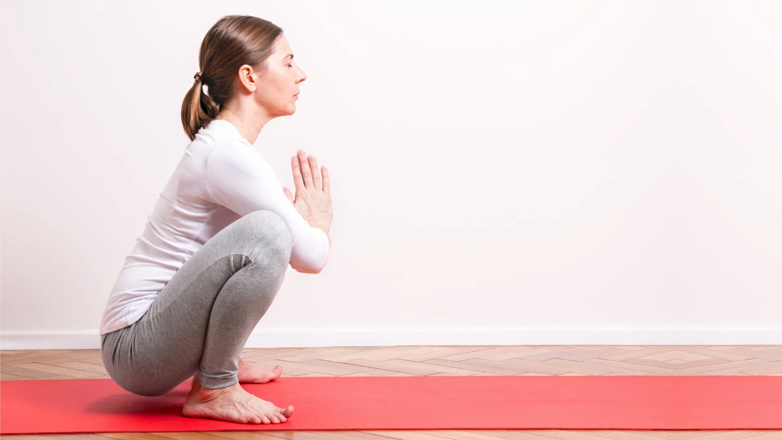 yoga instructor demonstrating yogic squat pose (in sanskrit: malasana) 